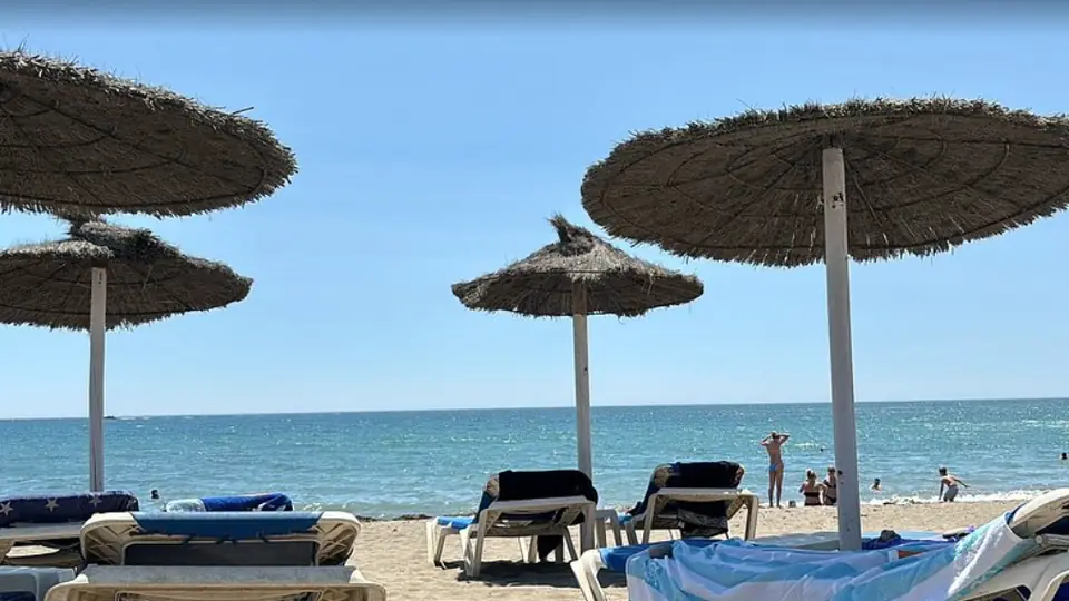 Hamacas y sombrillas de brezo del Chiringuito África Beach en la arena de la playa de La Rada, con el mar al fondo